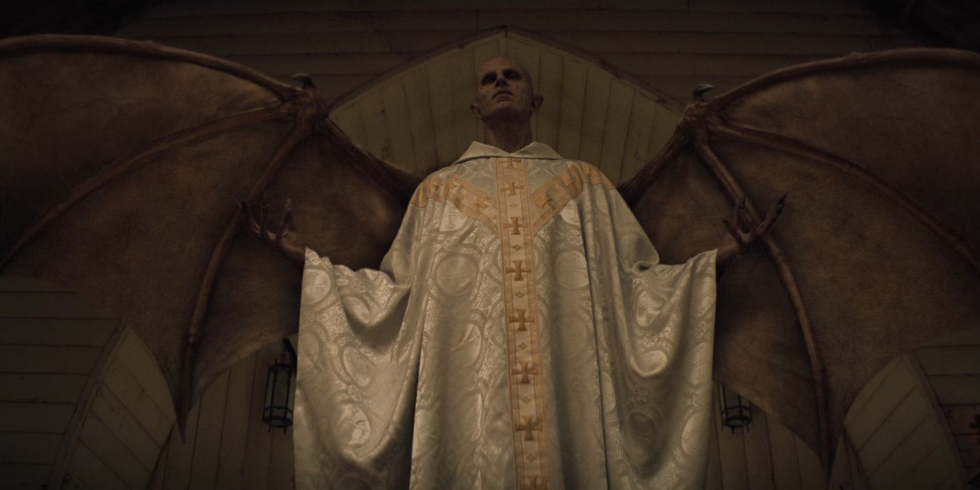 The "Angel" from Mike Flanagan's 'Midnight Mass in a priest's robes and standing under the dome of a church.