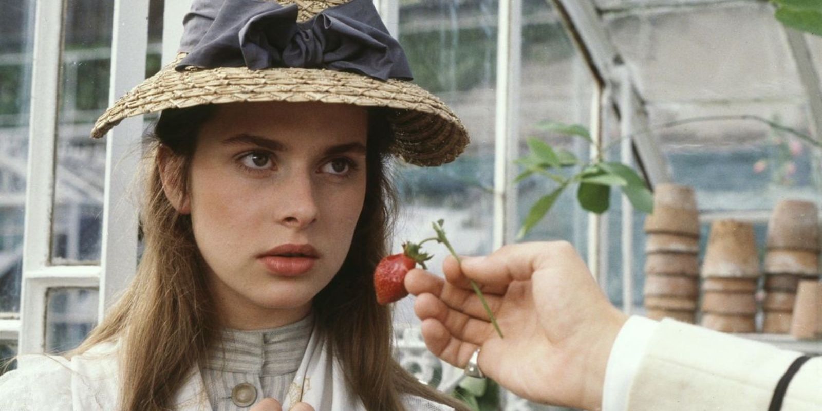 Nastassja Kinski looking serious while a hand reaches out to her face in Tess