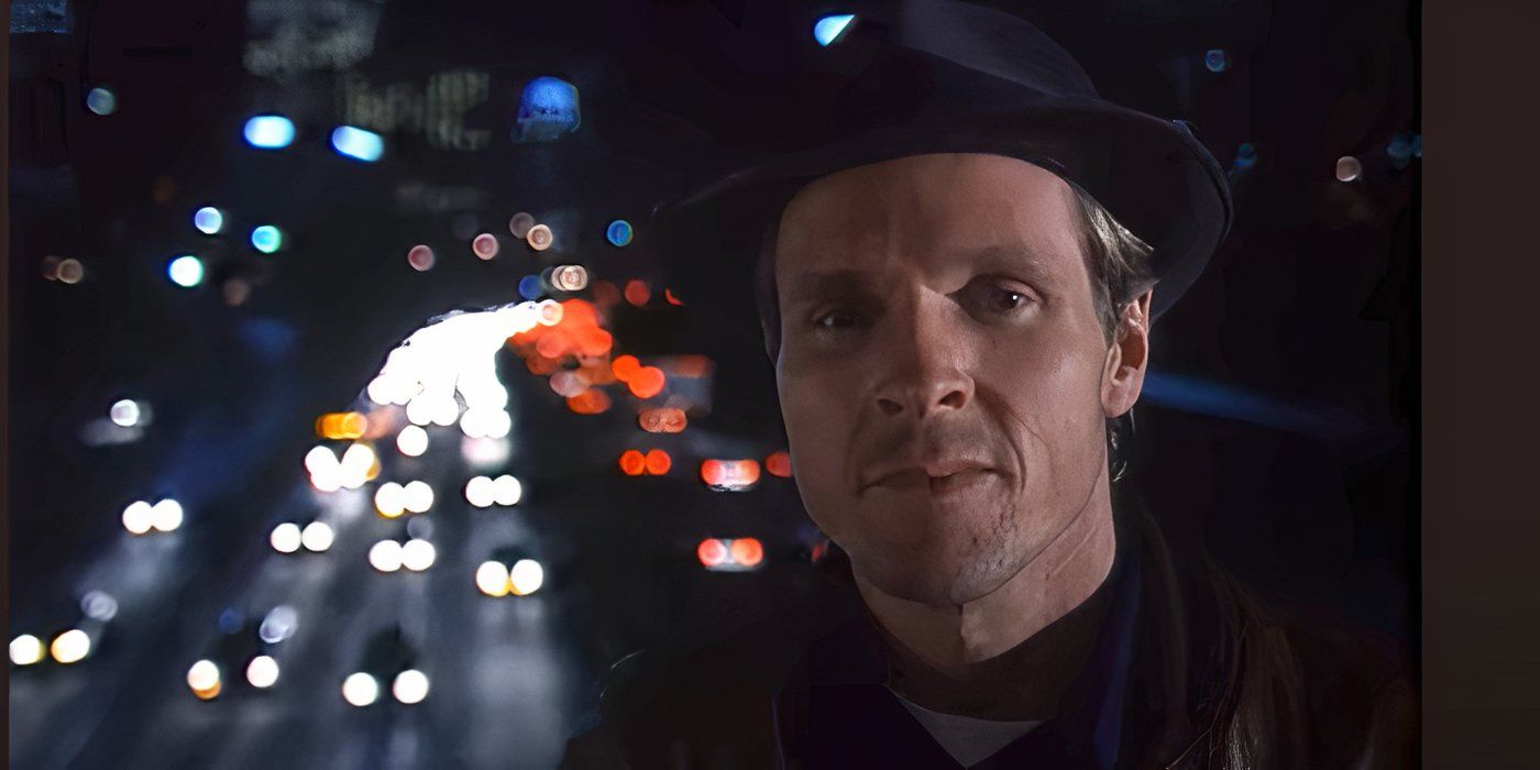 Niles Talbot speaks into the camera with the city highway in the background at night in Tales From the Crypt.