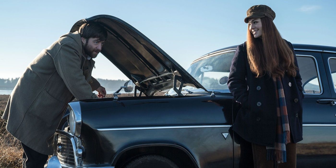 Sophie Skelton as Brianna leaning against a car with Richard Rankin as Roger under the hood in Outlander