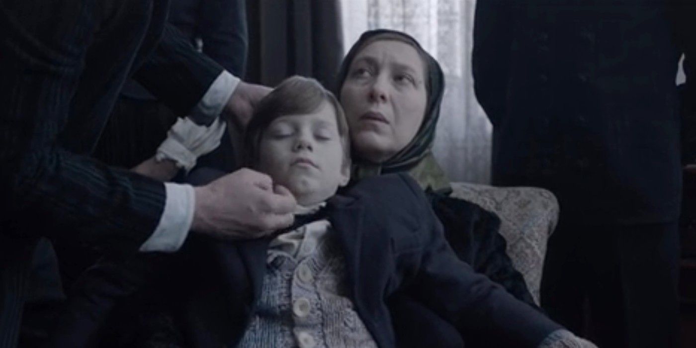 A woman holds the body of a boy for a photograph while a man adjusts the boy&rsquo;s head in &ldquo;Post Mortem&rdquo; (2020)