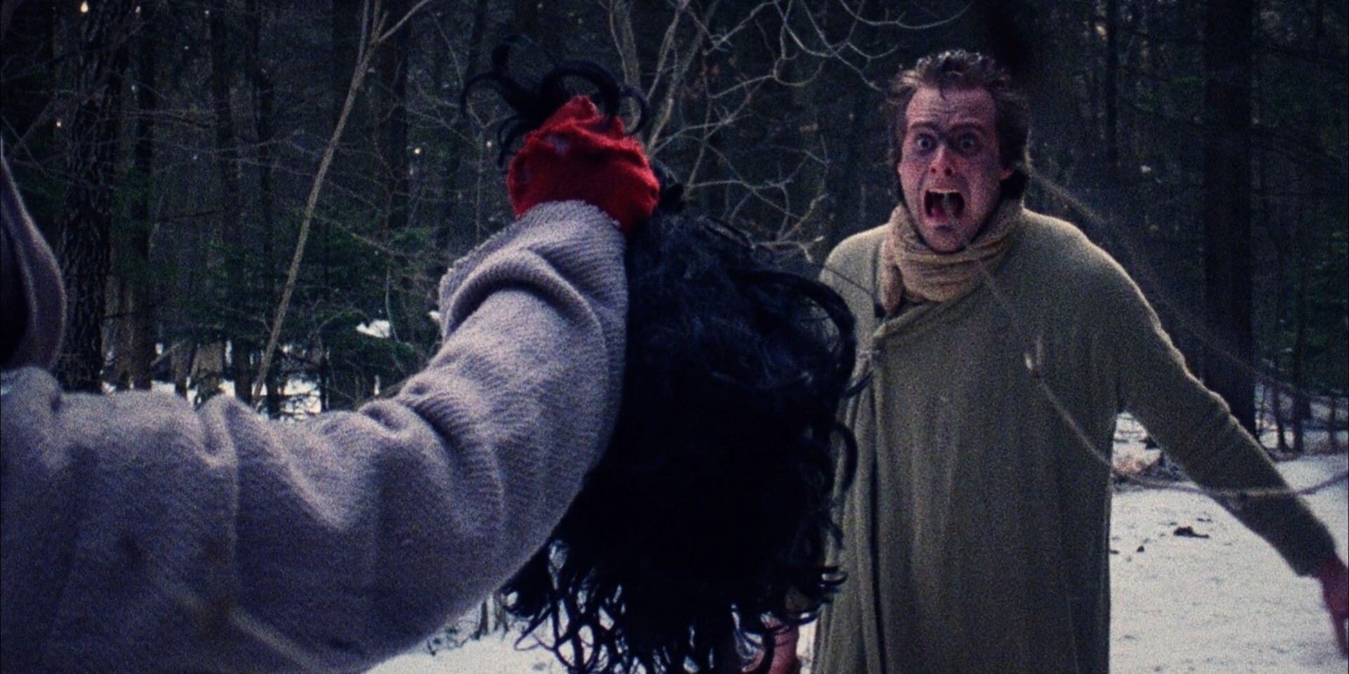 A man in the middle of a snowy forest screaming in anguish as another man is holding up a severed head to show him in 'Premutos: The Fallen Angel' (1997)