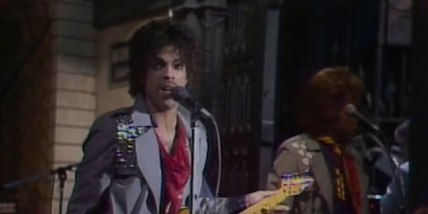 Prince singing into a microphone and performing with a band on the stage of Saturday Night Live.