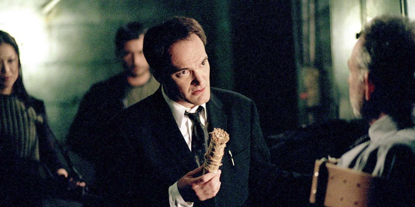 Quentin Tarantino as agent Cole holds an object and talks to a man who is strapped down in Alias.