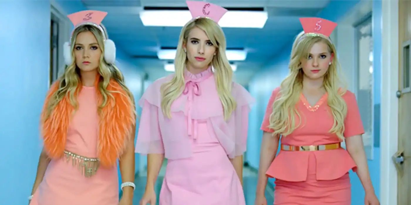 Billie Lourd, Emma Roberts, and Abigail Breslin (The Plastics) strutting down a hallway in colorful nurse costumes. 