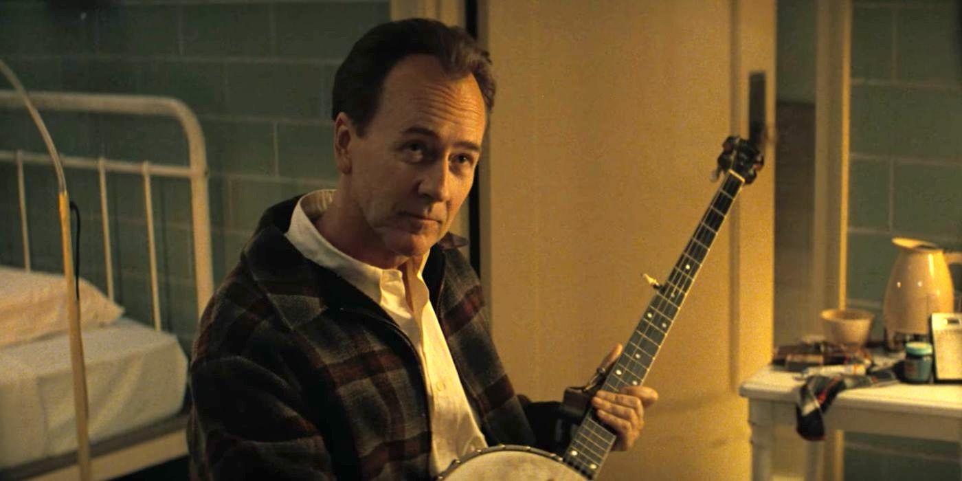 Folk music icon Pete Seeger (Edward Norton) holds a banjo in A Complete Unknown (2024).