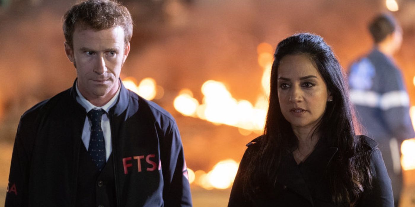 Mark Rendall as Theo and Archie Panjabi as Kendra Malley standing in front of a fiery crash site in 'Departure'