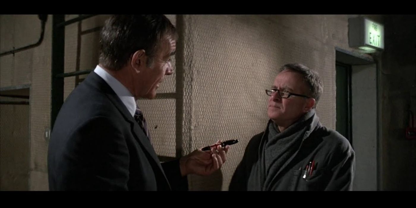 James Bond holding a deadly pen that Q showed him moments ago, while talking to Q about it