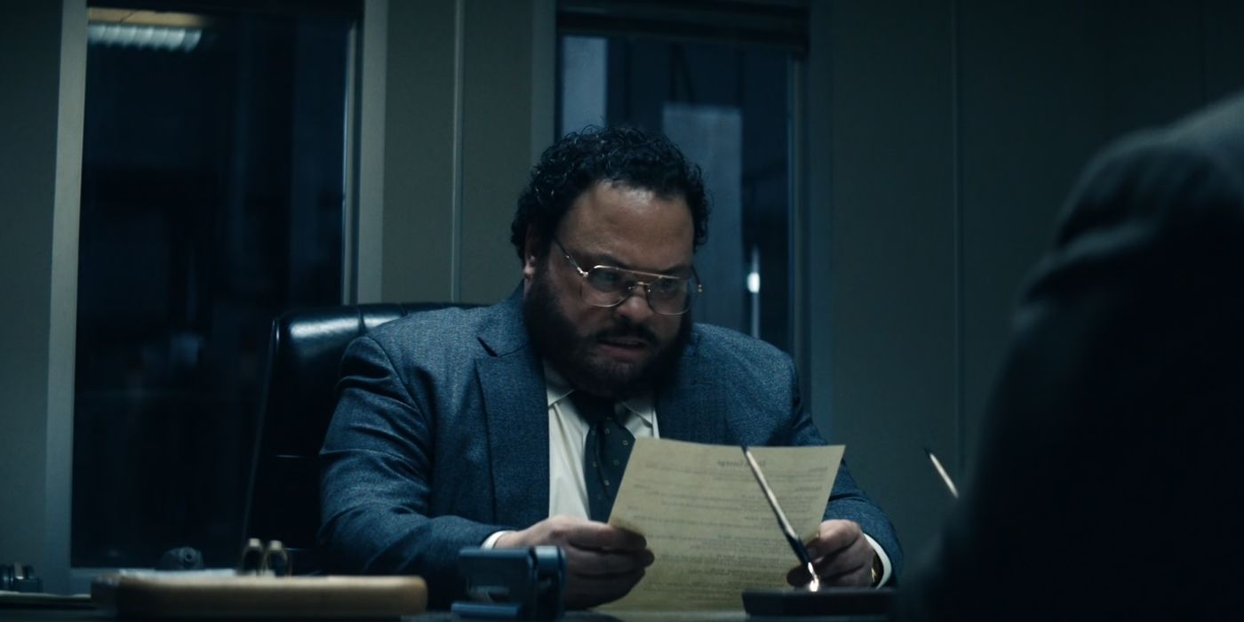 Adrian Martínez reads a resumé in front of Zach Cherry in Severance Season 2