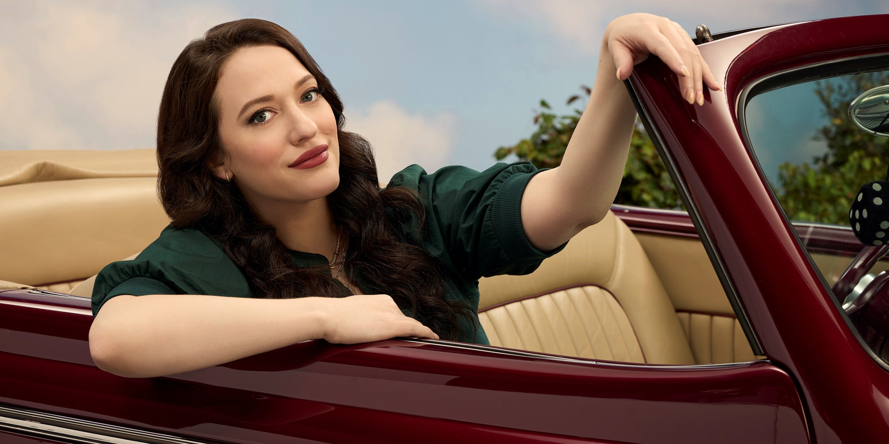 Kat Dennings as Riley in an ABC promo shoot in a convertible car with her left hand up in Shifting Gears