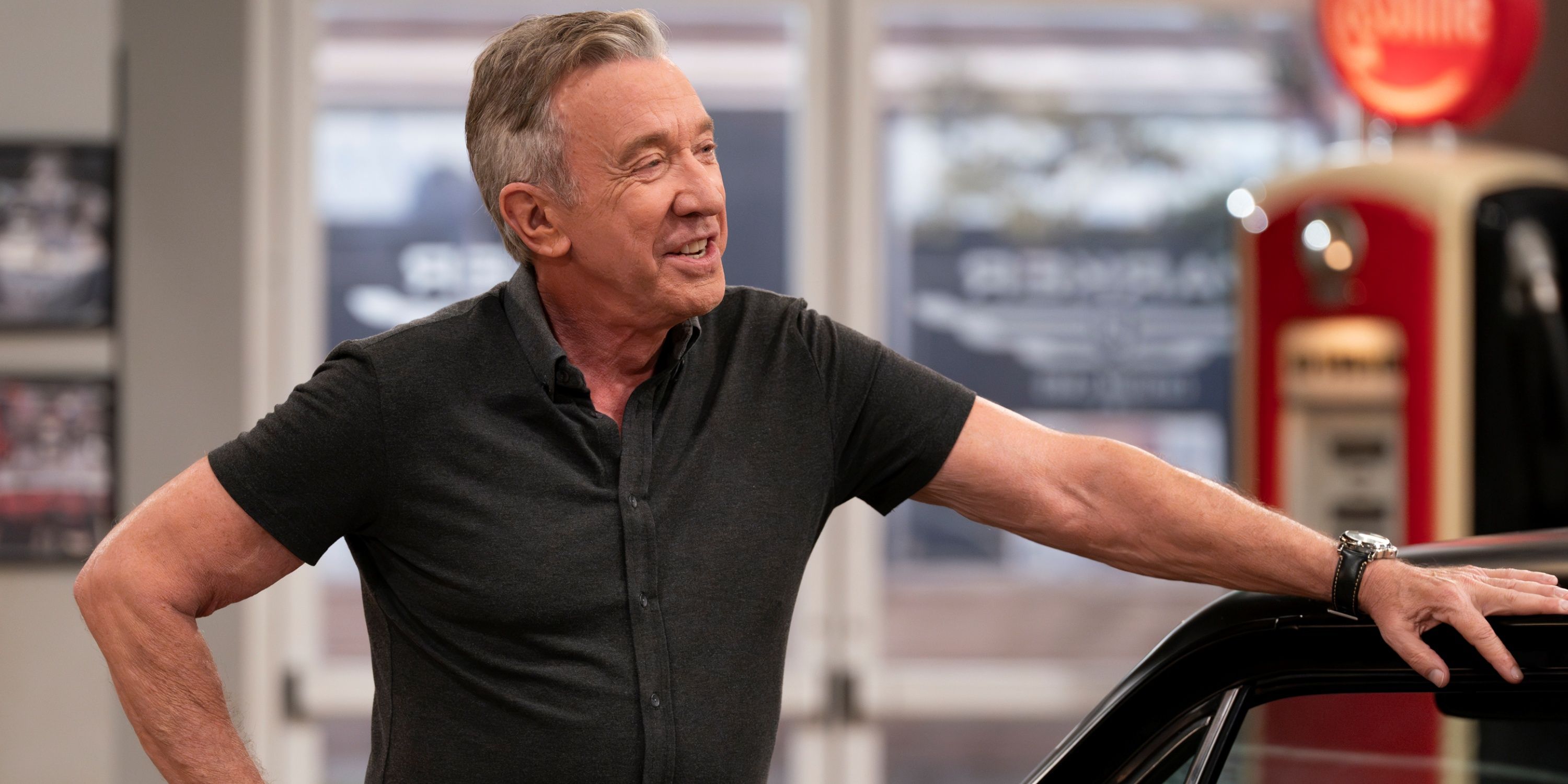 Tim Allen as Matt leaning on the top of a car with his left arm in his auto shop in Shifting Gears.