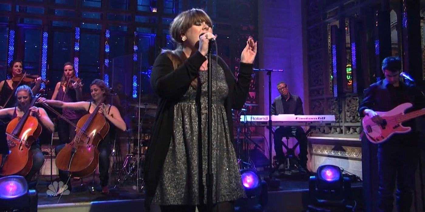 Adele singing passionately into a mic on stage on SNL