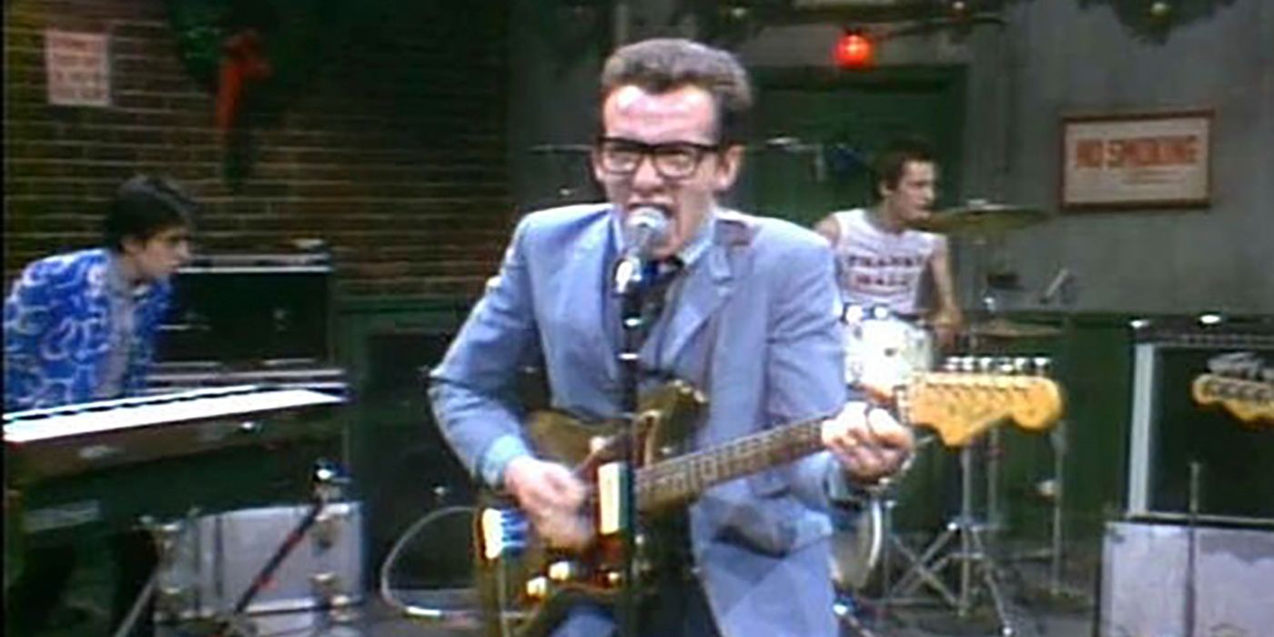 Elvis Costello holding a guitar and singing into a mic on SNL.