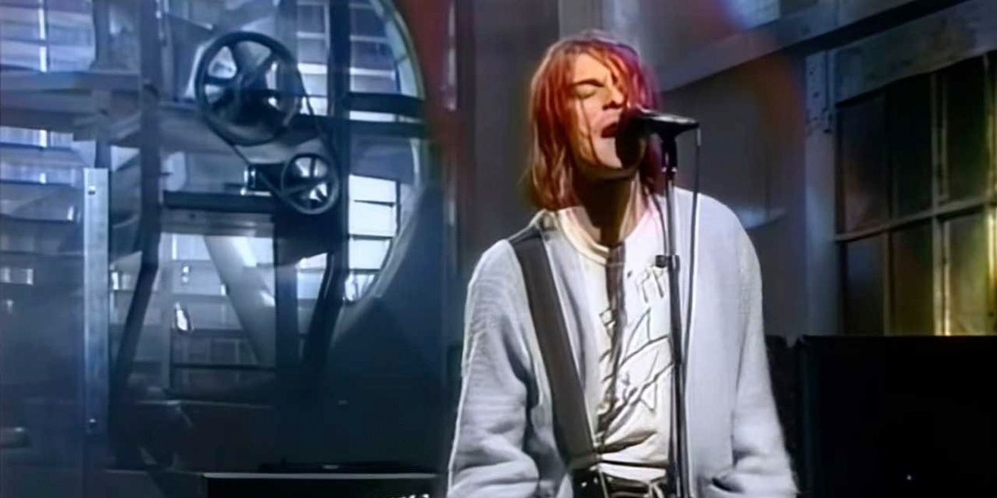 Kurt Cobain singing on stage on Saturday Night Live, his red hair in front of his face.