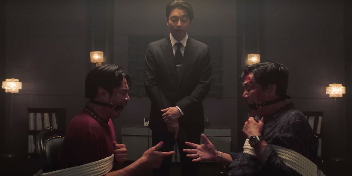 The Salesman (Gong Yoo) watches Woo-seok (Jun Suk-ho) and Dae-pyo (Kim Pub-lae) play Rock, Paper, Scissors Minus One in Squid Game 2