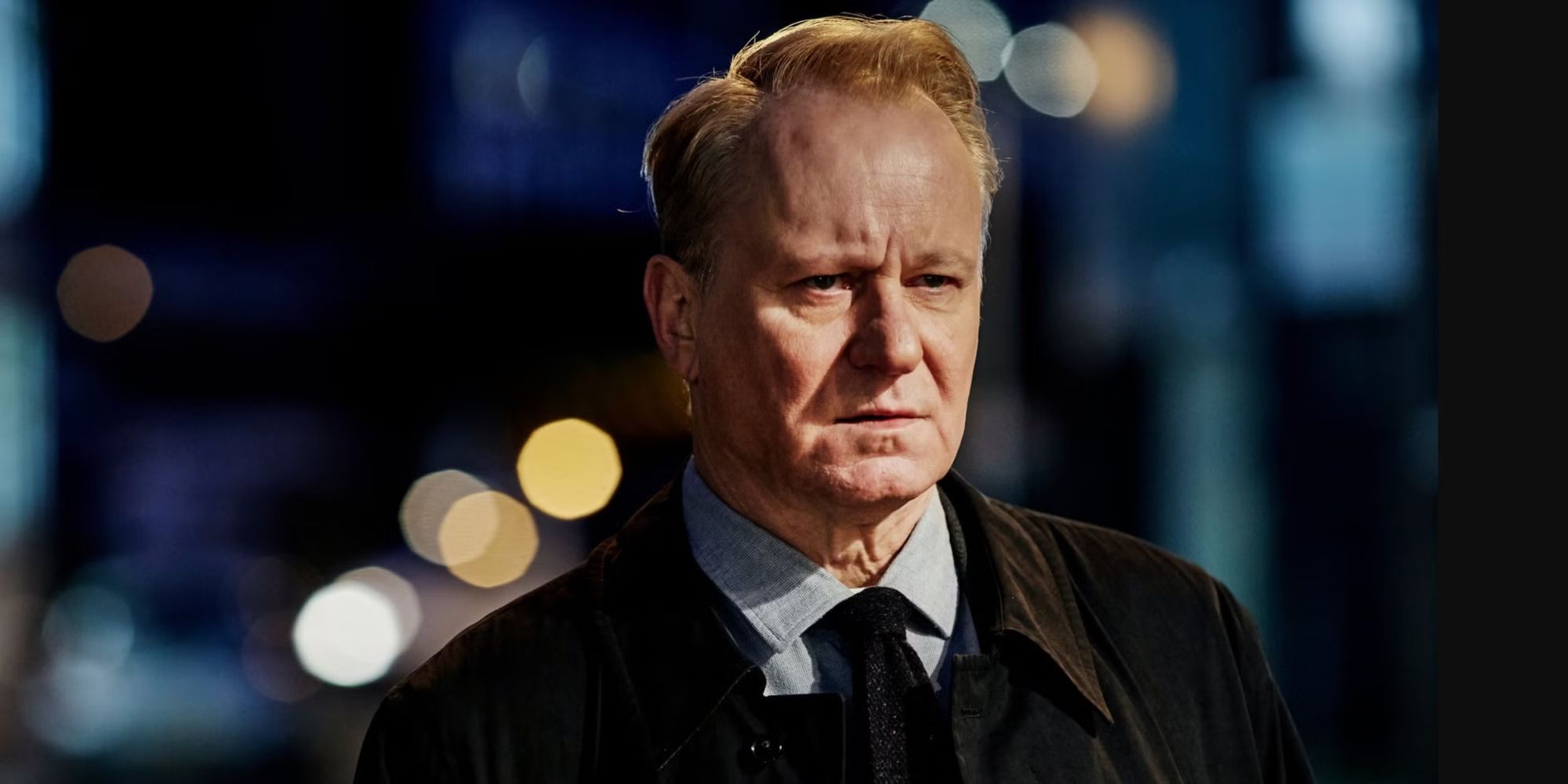 Stellan Skarsgård as DI John River looks into the distance with a city behind him in River.