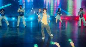 Dae standing in the center of the stage, with his friends behind him in matching outfits -- Juliana, Q, Kitty, Yuri, and Jin -- in the Season 2 finale of XO, Kitty