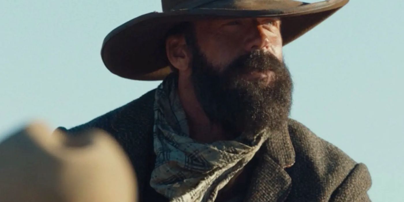Taylor Sheridan as Charles Goodnight with a large beard, bandana around his neck, and cowboy hat in 1883.