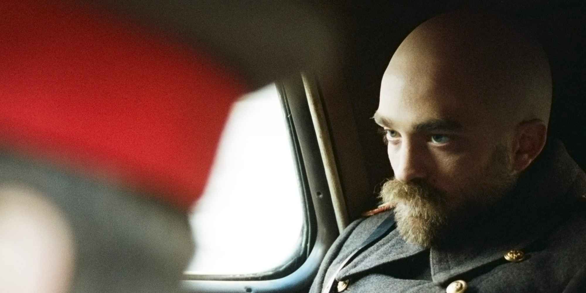 Robert Pattinson as adult Prescott, sitting in the backseat of a car in &lsquo;The Childhood of a Leader&rsquo;.