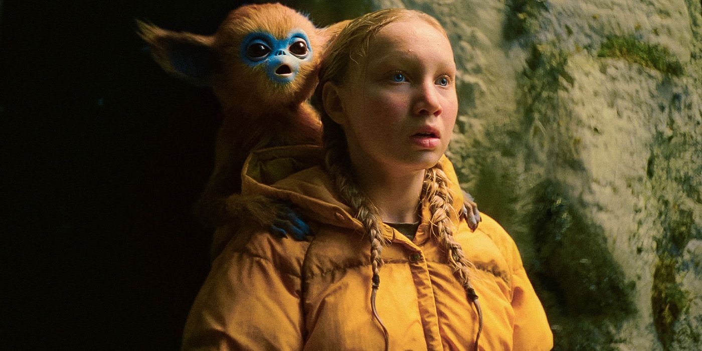 Yuri (Helena Zengel) in a yellow jacket with a brown and blue creature on her shoulder in The Legend of Ochi