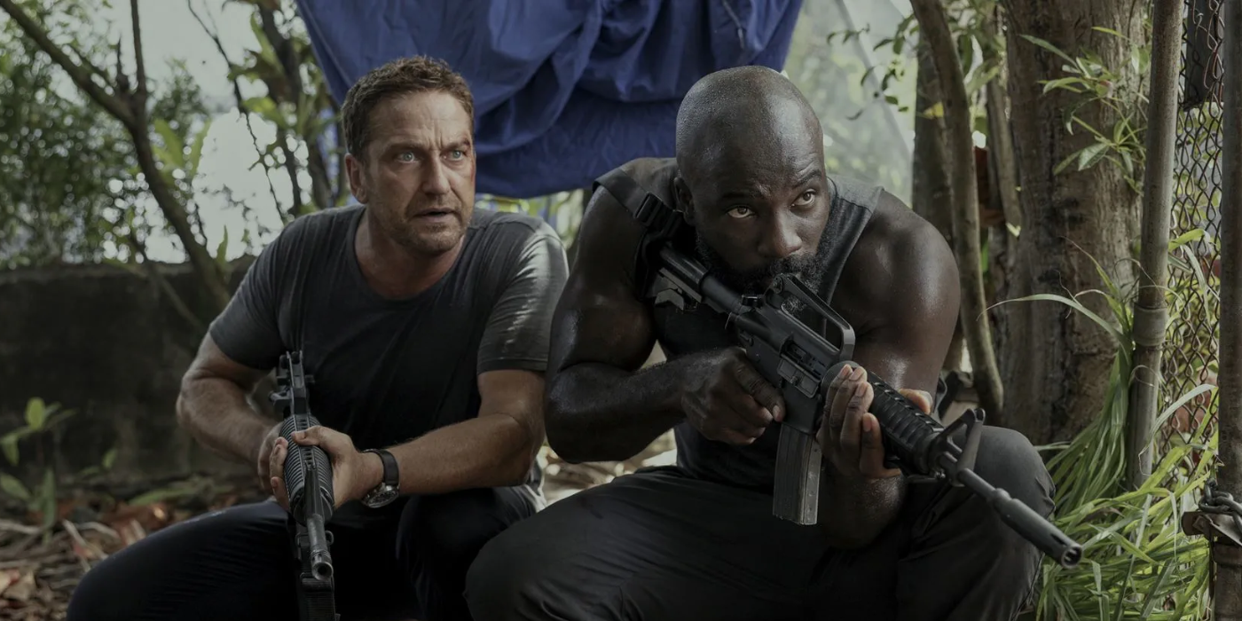 Gerard Butler and Mike Colter wield machine guns in a jungle in Plane (2023).