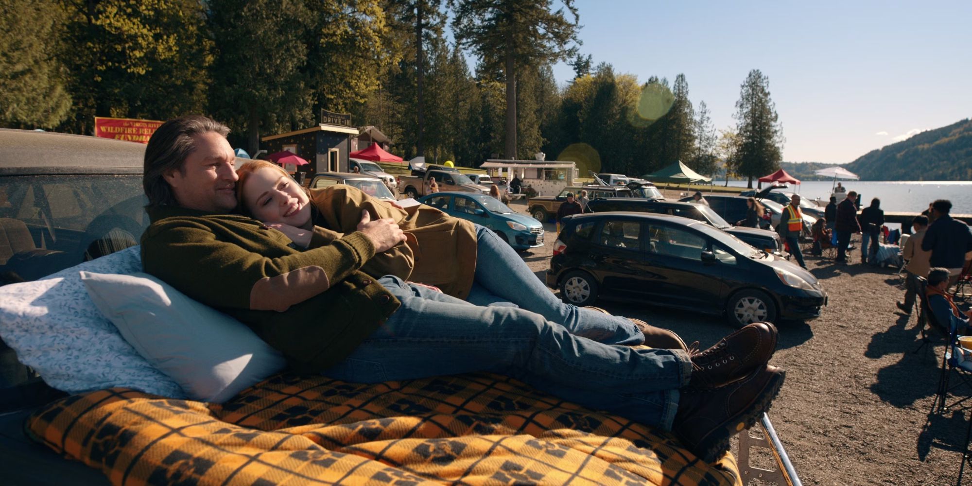 Mel and Jack cuddle together on the hood of a car at an outdoor event in Virgin River season 6.