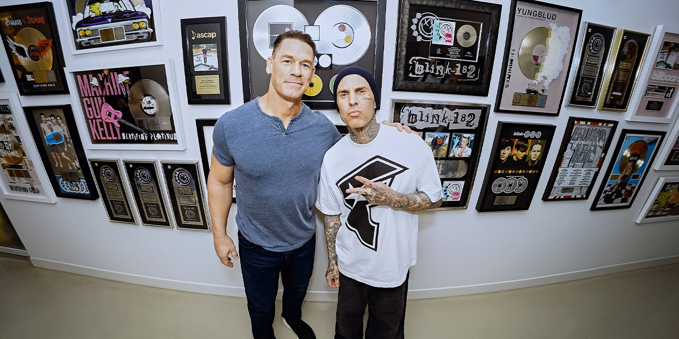 John Cena and Travis Barker posing together in a hallway with record awards in What Drives You