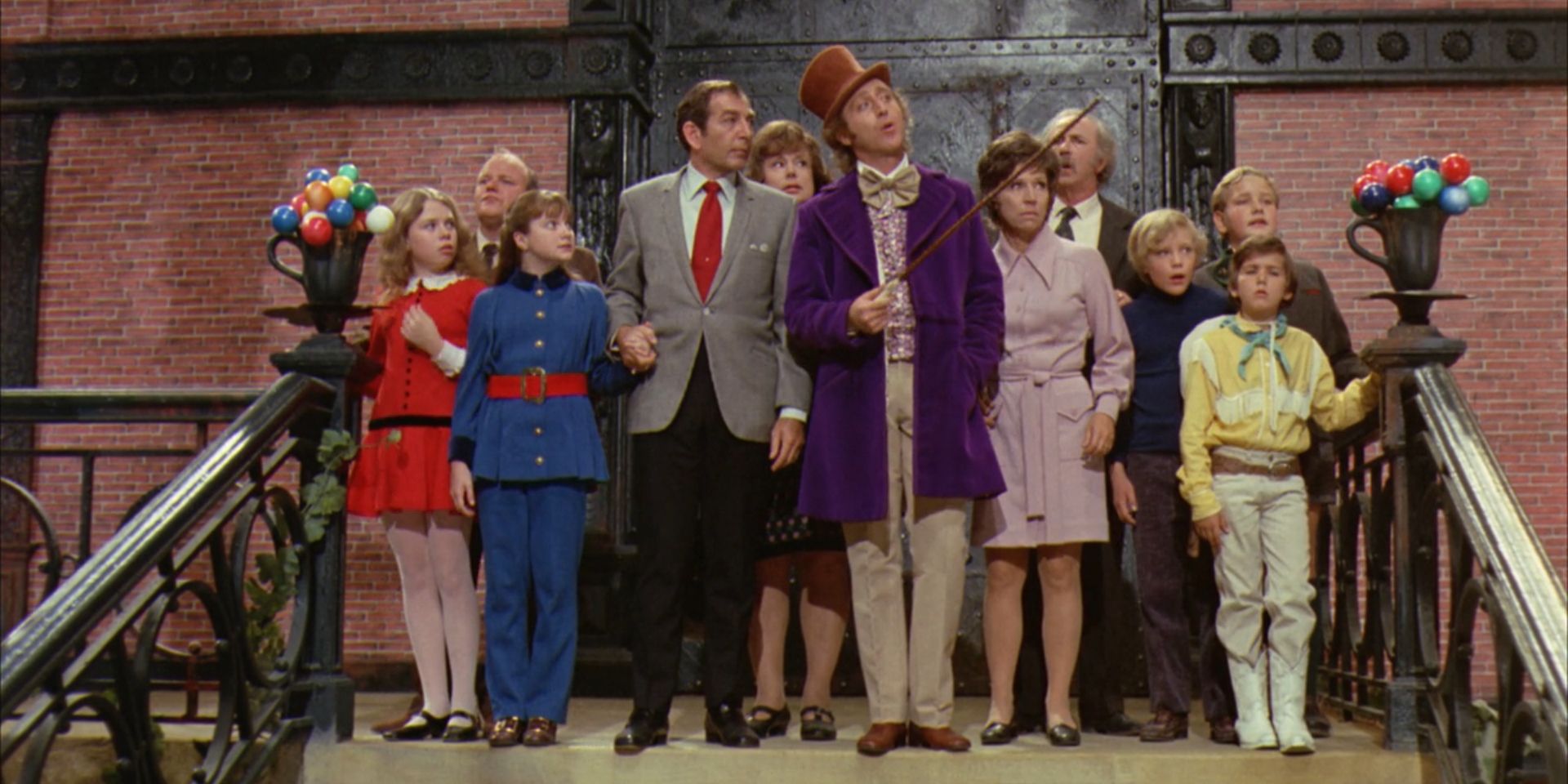 The ensemble cast of 'Willy Wonka & the Chocolate Factory' stands together and Wonka motions with his cane.