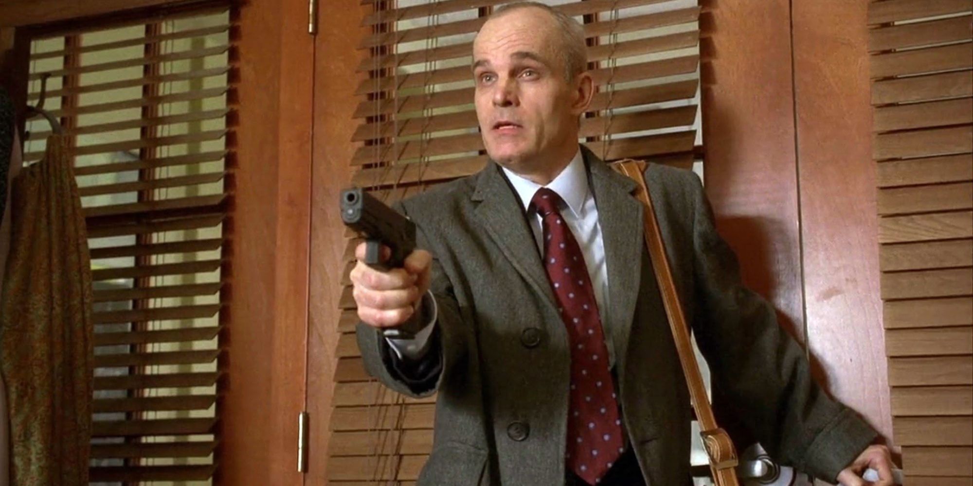 Zeljko Ivanek standing in front of a closed door pointing a gun in House episode Last Resort
