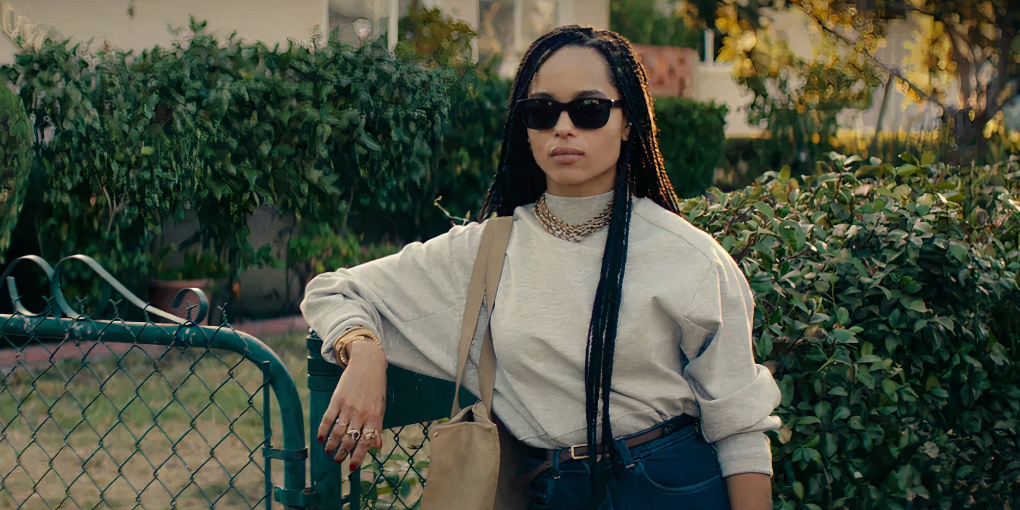 Zoë Kravitz as Nakia in Dope leaning against a wire fence with sunglasses on.
