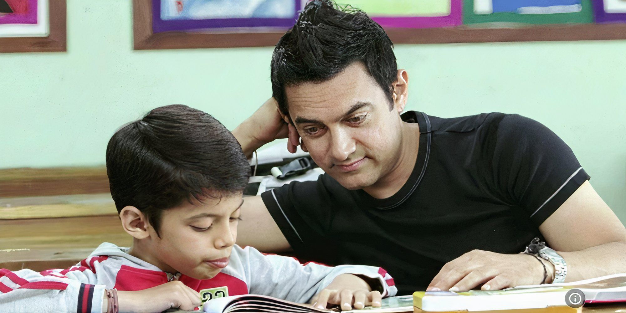 aamir khan and darsheel safary from taare zameen par are sitting and reading a book.