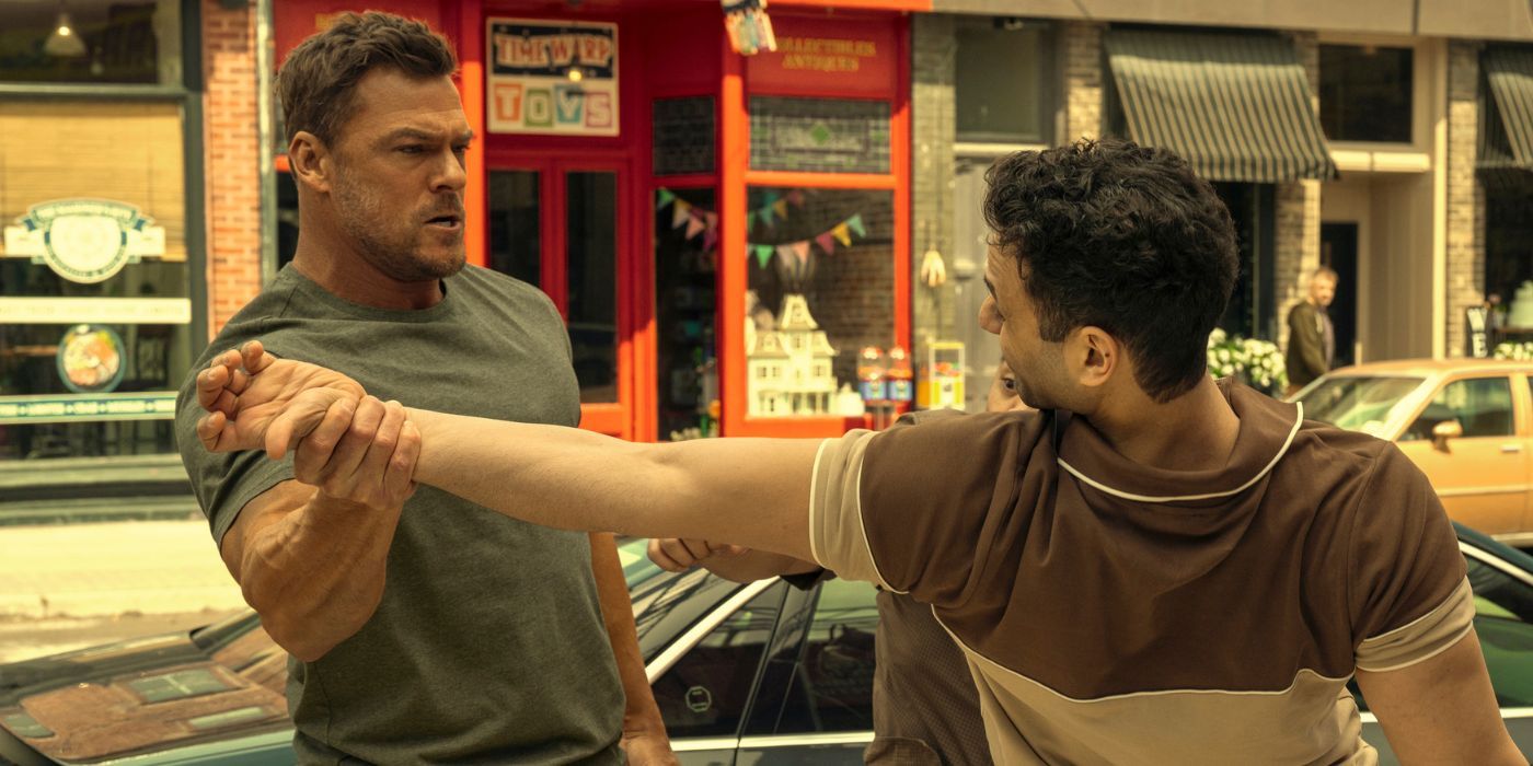 Alan Ritchson as Reacher, twisting a man's arm in the street.