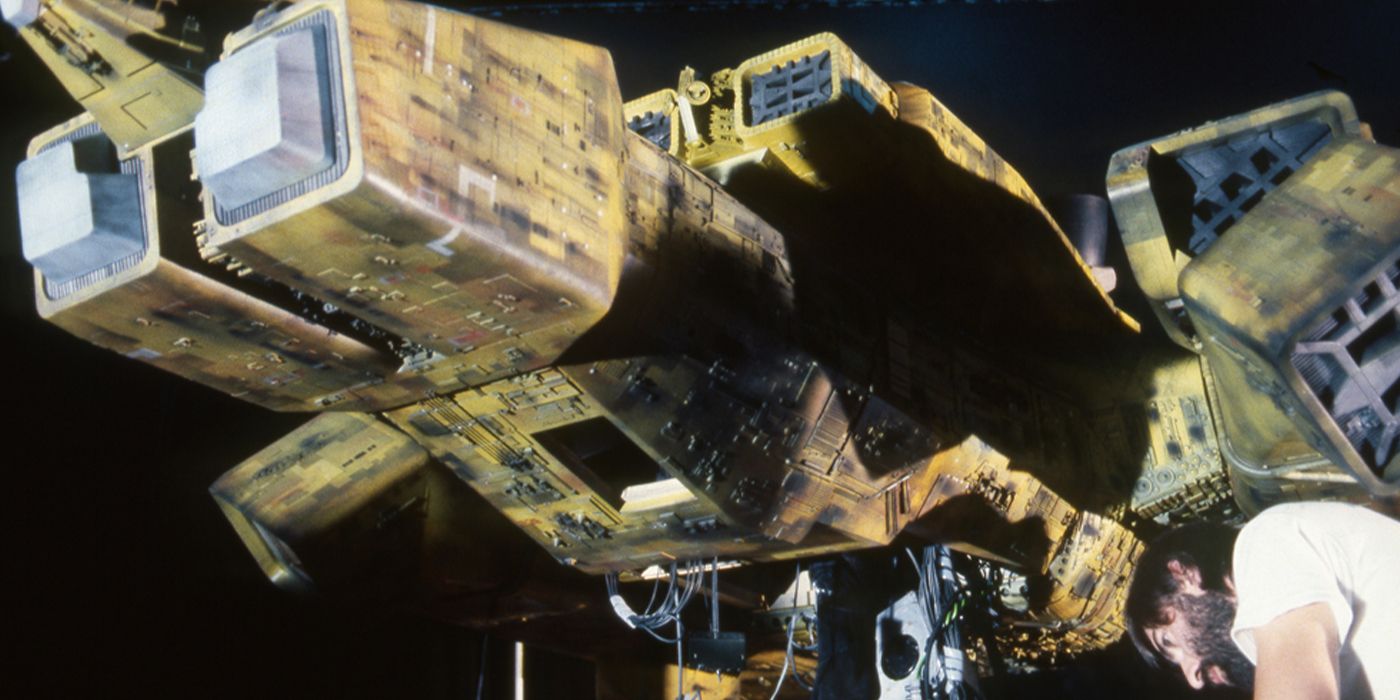 A behind-the-scenes photo of a crew member working on a ship model on the set of Alien (1979)