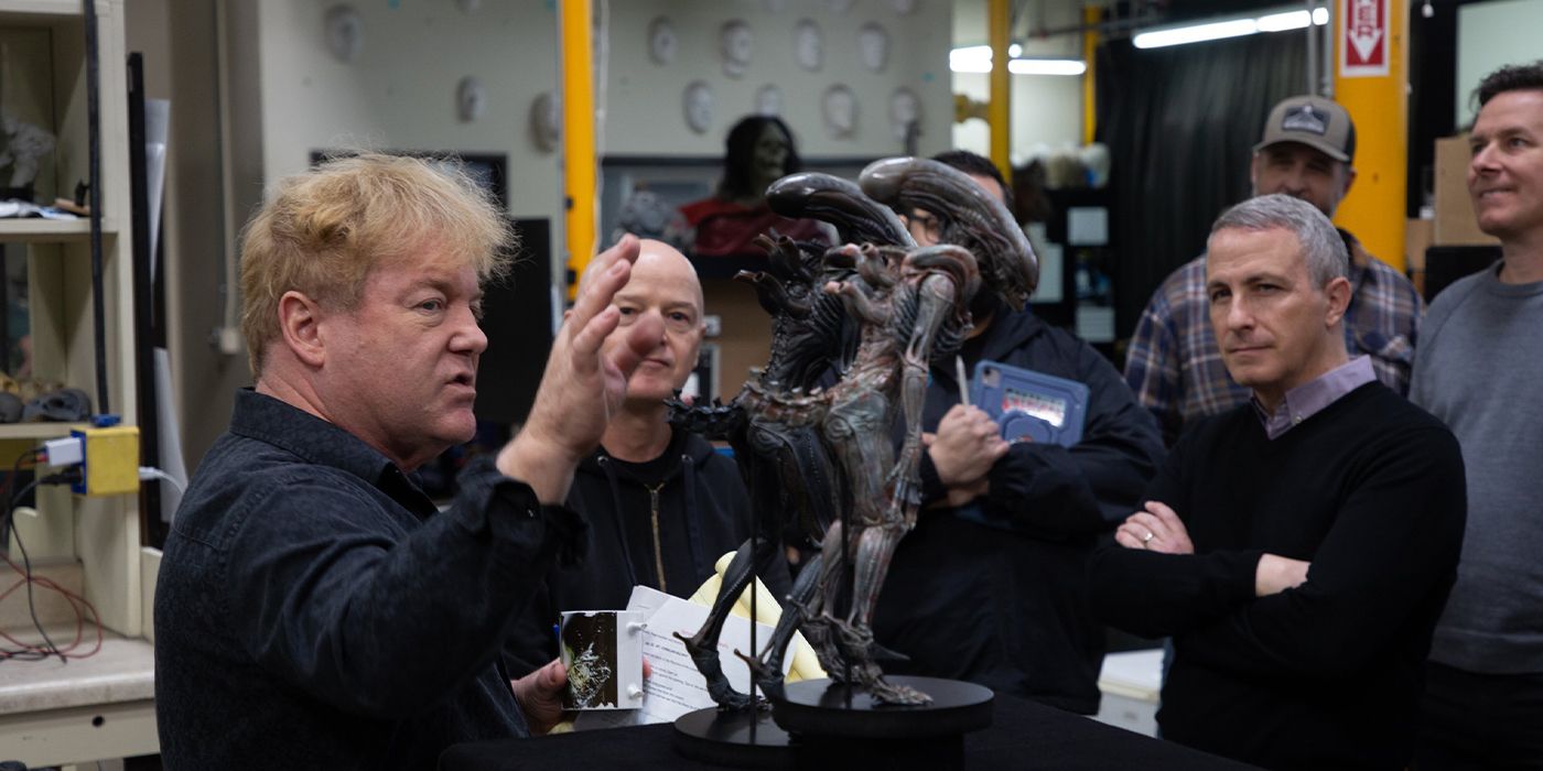 Shane Mahan on the set of Alien: Romulus explaining something with a small Xenomorph model