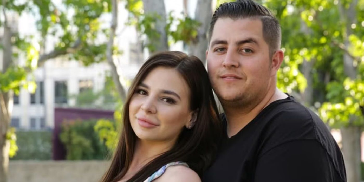 Jorge Nava and Anfisa Arkhipchenko from 90 Day Fiancé look at the camera and pose outside with trees behind.