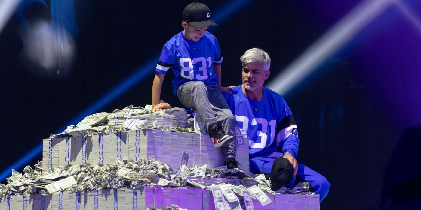 Player 831 sits on his pile of money with his son on the finale of &lsquo;Beast Games.'