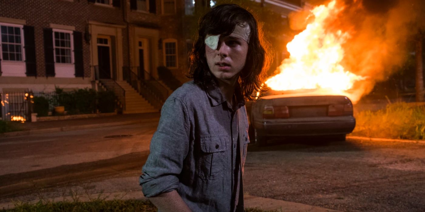 Chandler Riggs as Carl looking back at something as a car burns in season 8, episode 8 of The Walking Dead.