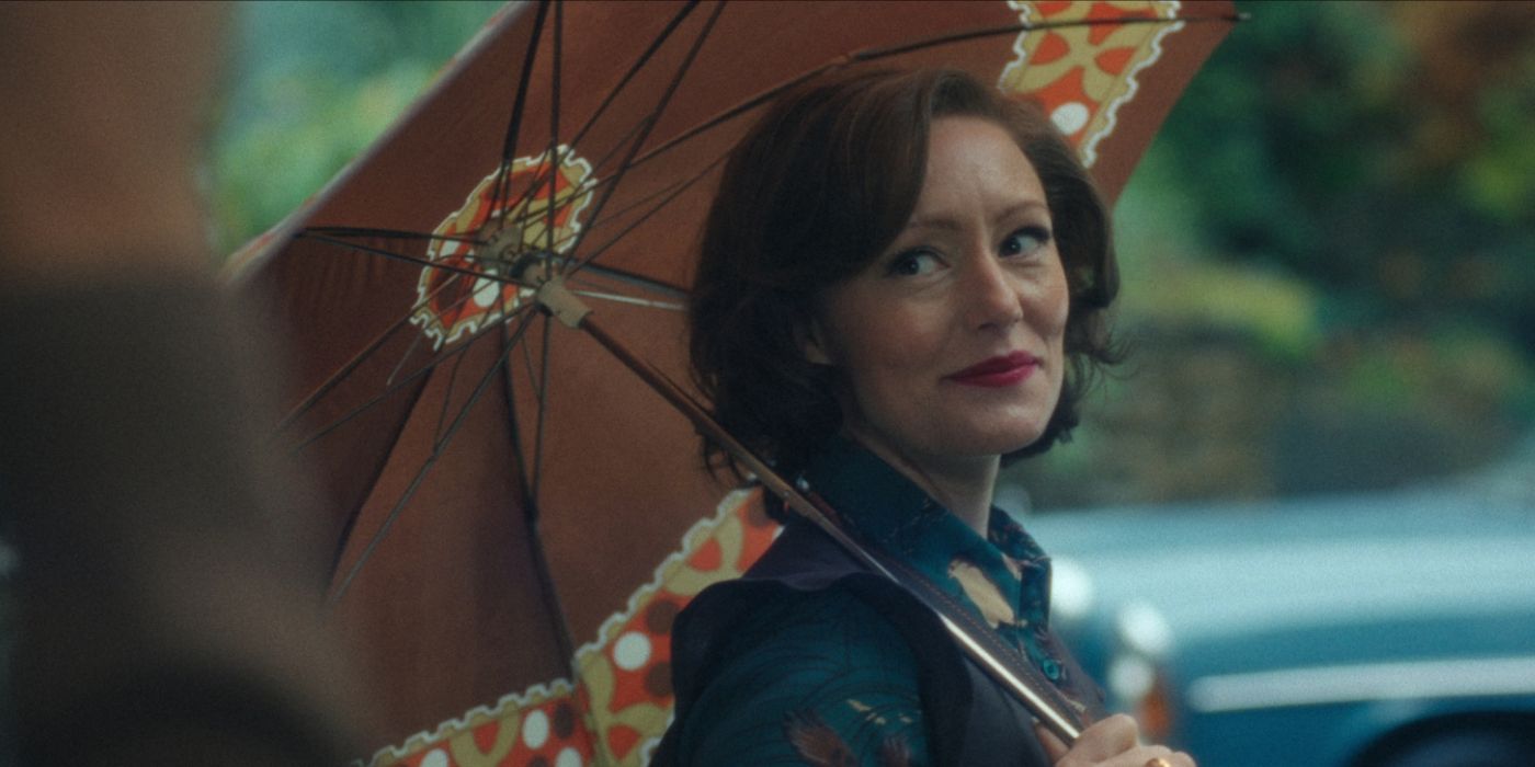 Cassandra (Lavinia Wilson) smiling and holding an umbrella over her head in Cassandra