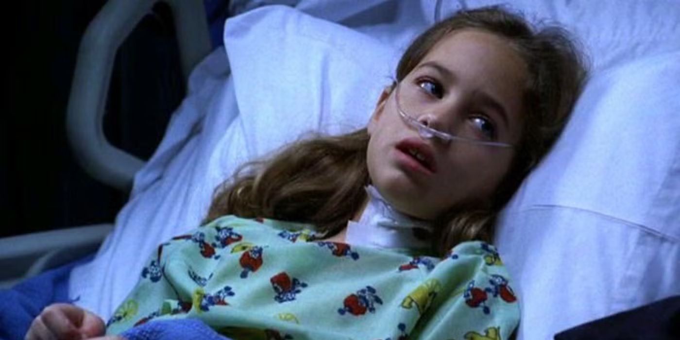 A young girl in a hospital bed with a breathing tube looks at someone off-camera in CSI episode Gum Drops.