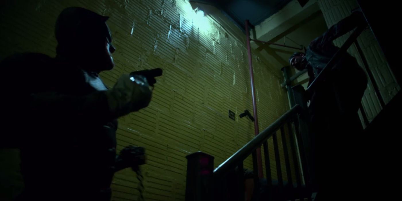 Daredevil pointing a gun at someone in a stairwell in Daredevil
