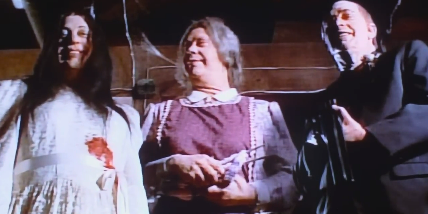 Tim Curry as The Bracketts, from left, Winona, Ma Brackett, and Pa Brackett, who stand smiling down at Judd in his grave