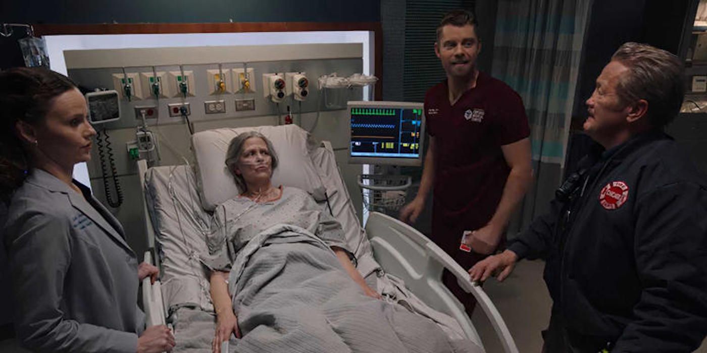 Dr. Lenox (Sarah Ramos), Dr. Ripley (Luke Mitchell), and Mouch (Christian Stolte) surround Trudy (Amy Morton) in her hospital bed in the One Chicago crossover "In the Trenches."