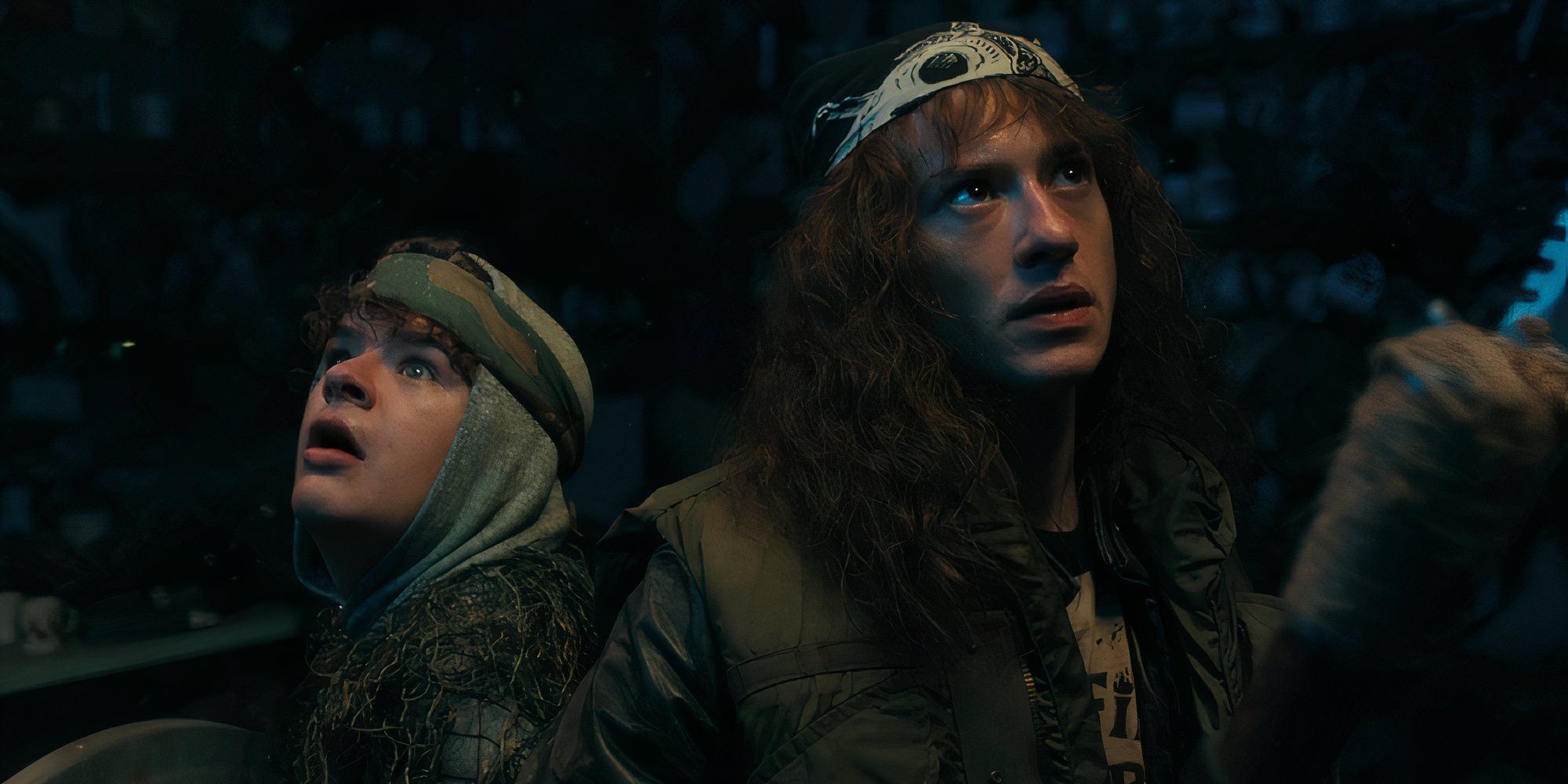 Gaten Matarazzo&rsquo;s Dustin and Joseph Quinn&rsquo;s Eddie with their back turned on each other look around with a concerned look on their faces in Stranger Things