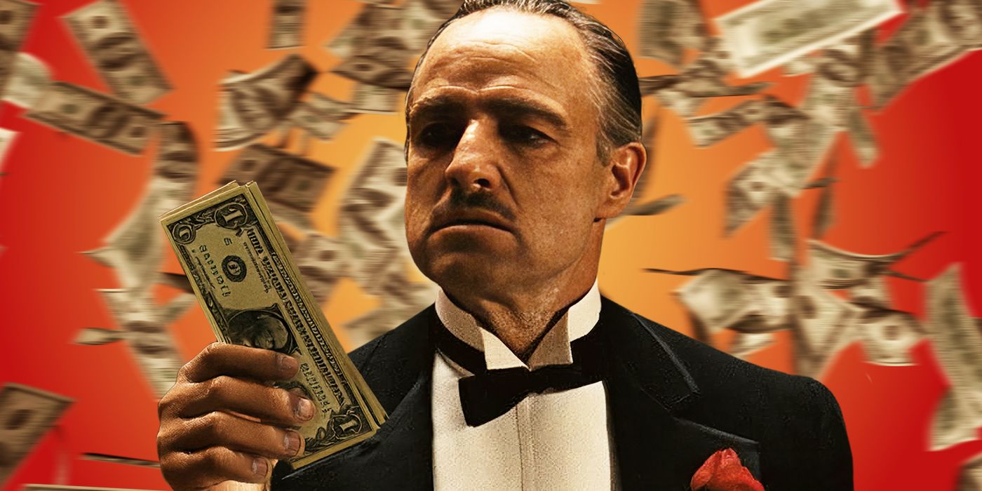 Marlon Brando as Vito Corleone, holding a wad of dollar bills while money falls around him.