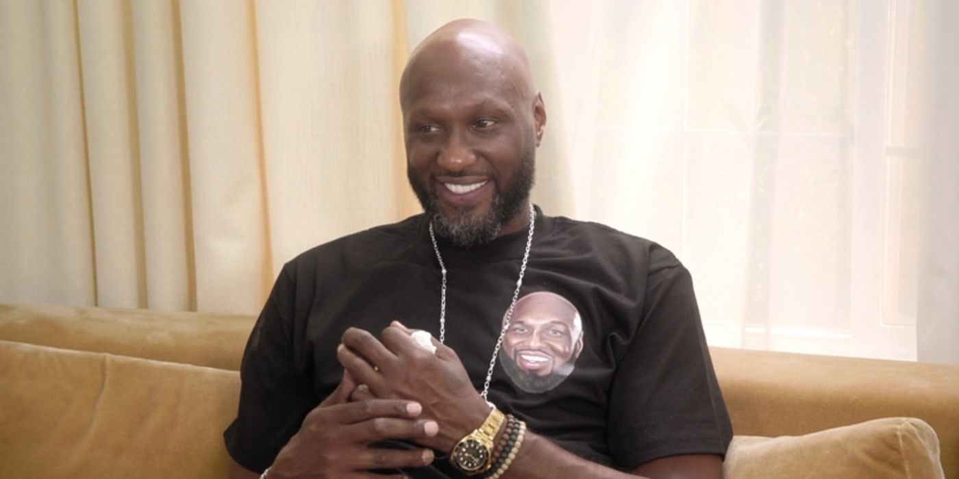 Lamar Odom grinning and playing with his hands while sitting on a couch on &lsquo;The Kardashians&rsquo;