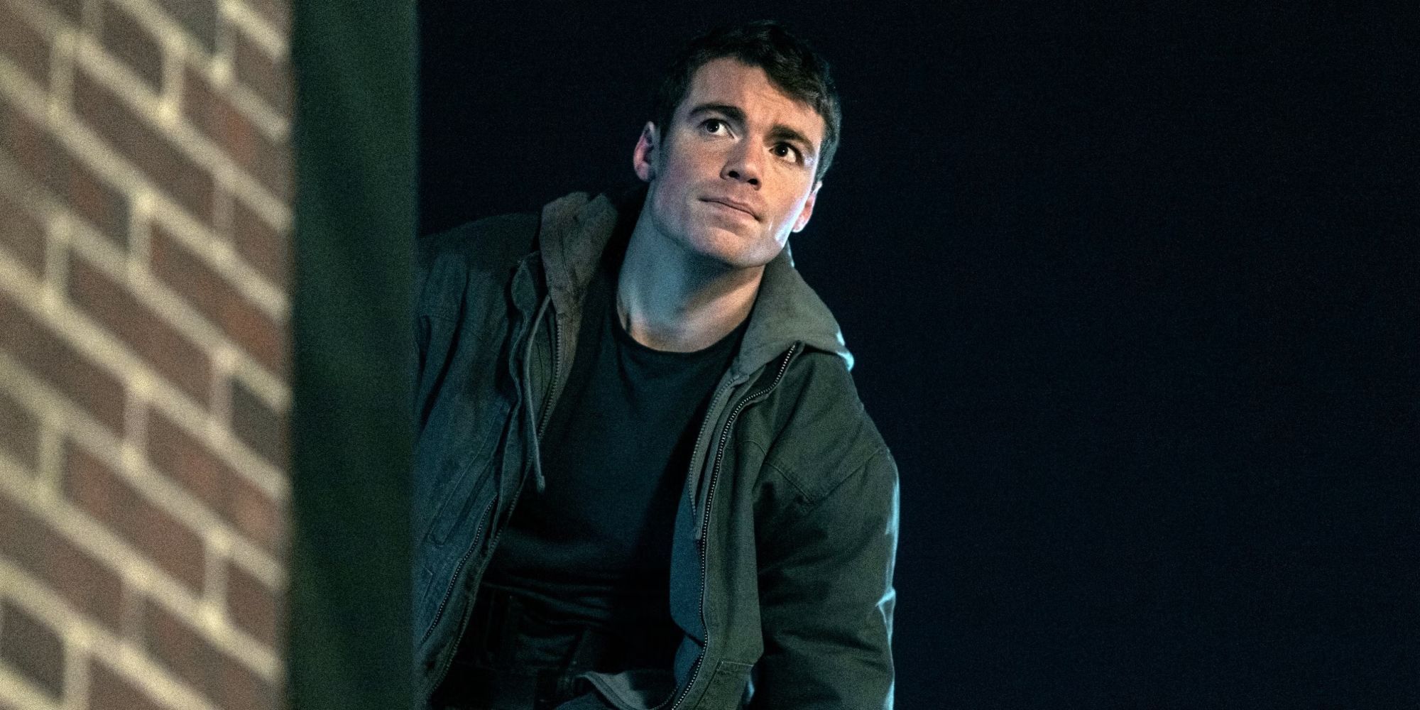 Gabriel Basso as Peter Sutherland outside next to a brick wall in Season 2 of The Night Agent.