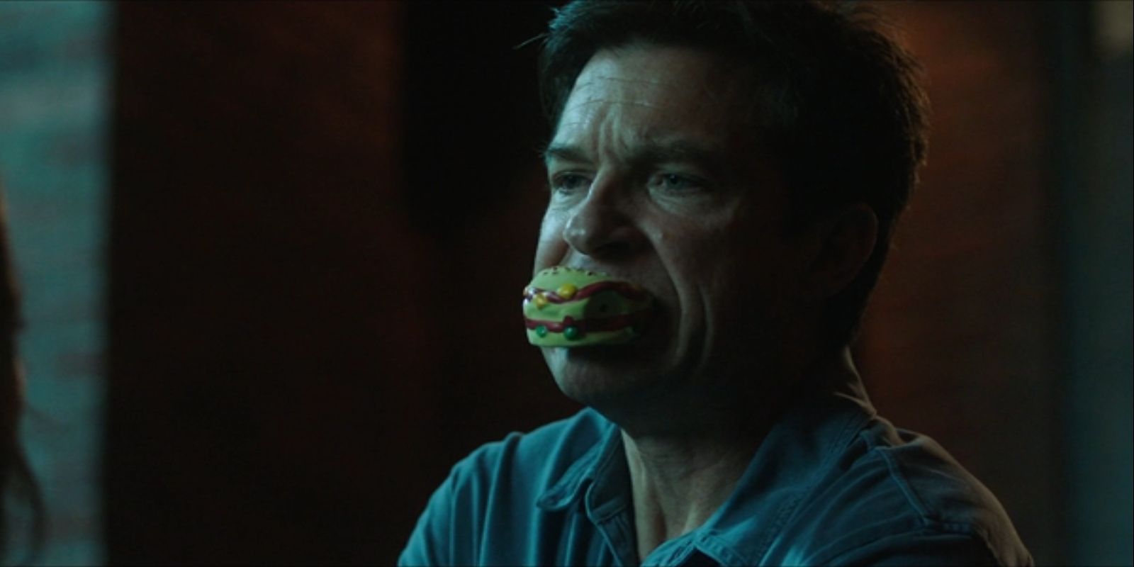 Max Davis, played by Jason Bateman, holds a squeaking dog toy in his mouth in &lsquo;Game Night&rsquo;.