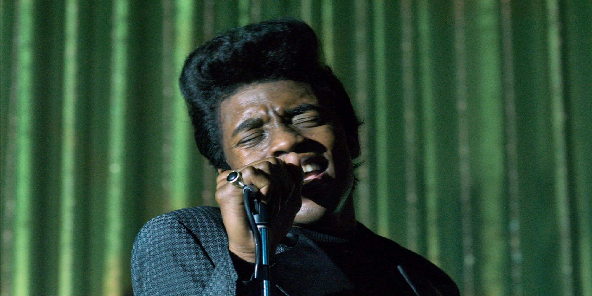 Chadwick Boseman as James Brown singing into a standing microphone in &ldquo;Get on Up&rdquo;.
