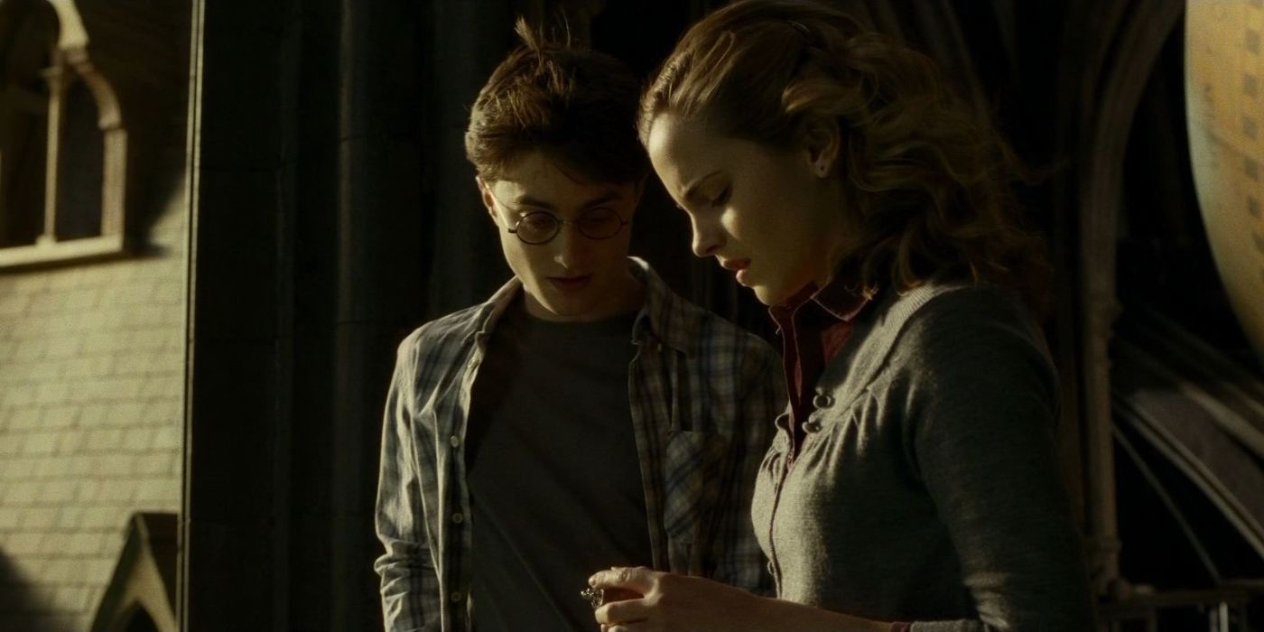 Harry (Daniel Radcliffe) and Hermione (Emma Watson) look down at the mysterious locket, with concern expressions on their faces.