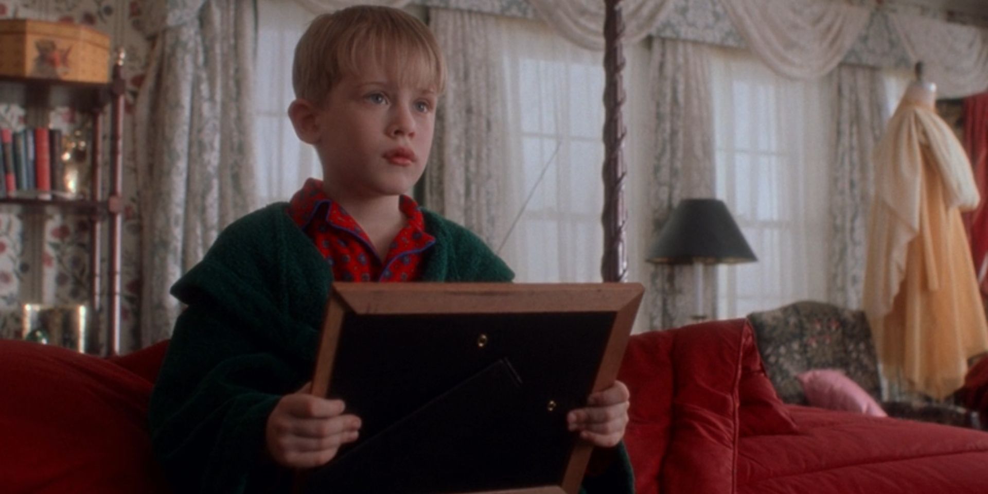 Kevin McCallister, played by Macaulay Culkin, looks up from a framed picture in 'Home Alone'.